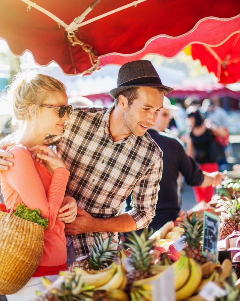 a young couple buying fruits and vegetables at a market