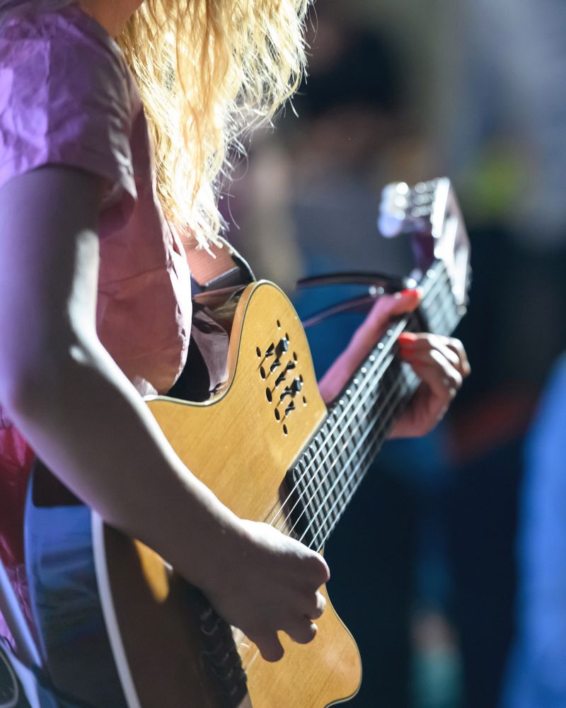Woman playing guitar at a concert in front of a crowd